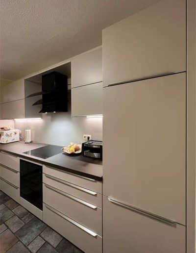 Eine Küchenzeile mit cremefarbenen Schubladen und Schranktüren und einer dunkelgrauen Oberflächenplatte.