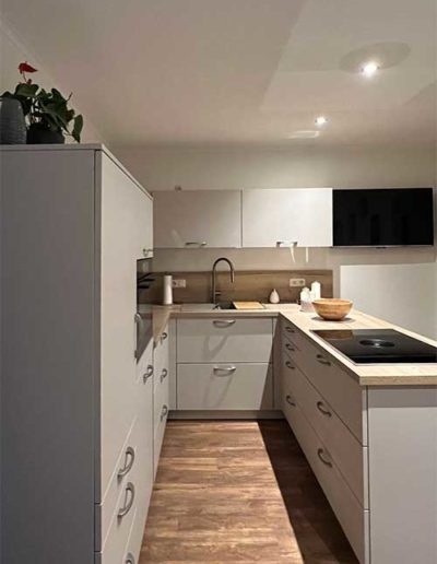 Eine graue Küchenzeile mit Holzoberfläche auf einem Parkettboden.