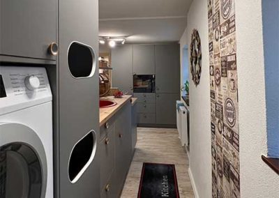 Eine schwarze Küchenzeile mit hölzernen Platten. Links in einem Küchenschrank ist eine Waschmaschine eingebaut.