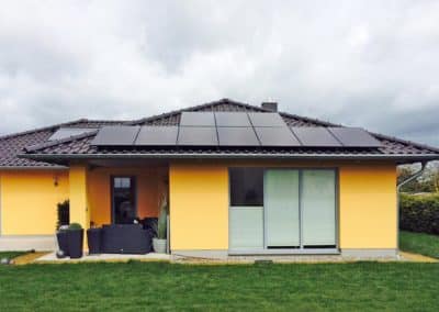 Ein gelbes Haus, dessen Dach teils mit Photovoltaik bedeckt ist.