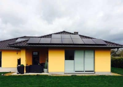 Ein gelbes Haus, dessen Dach teils mit Photovoltaik bedeckt ist.