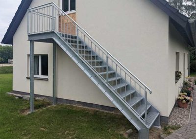 Eine Stahltreppe, welche an der Fassade eines Hauses zum ersten Stock führt.