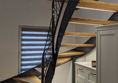 Eine Treppe mit schwarzem Stahlgeländer und hölzernen Stufen.