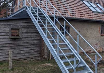 Eine Stahltreppe, welche an den ersten Stock eines Hauses führt.