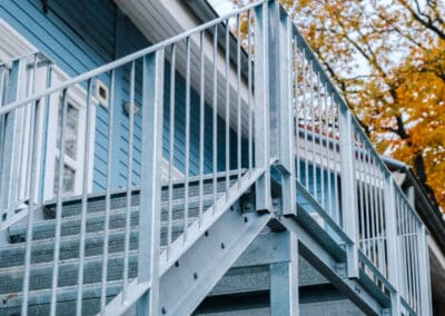 Stahltreppe mit Geländer an einem blauen Haus